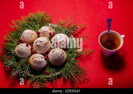 Una tazza di tè caldo con cucchiaio su sfondo rosso con cupcake natalizi ed elementi decorativi Foto Stock