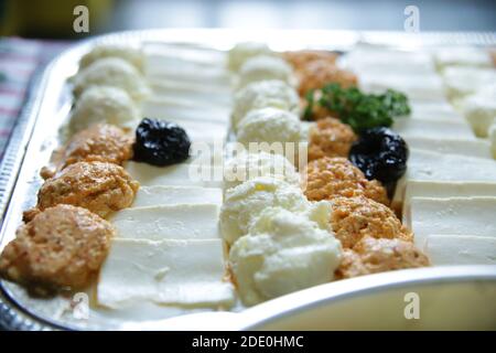 Diversi tipi di formaggio e crema disposti su un piatto mezza tavola da catering per diversi tipi di festeggiamenti.primo piano, sfondo sfocato. Foto Stock