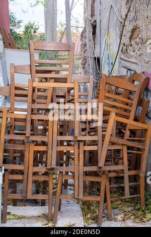 Gruppo sedie, chiuso il ristorante Covid-19 Pandemic Lockdown. Posti taverna in legno impilati all'esterno, verticali. Monastiraki, Atene Grecia Foto Stock