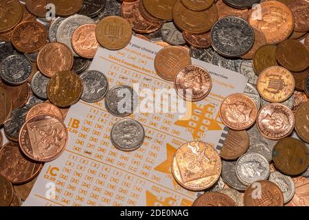 UK Euromilions Slip selezione lotteria circondato da monete di piccola denominazione Foto Stock