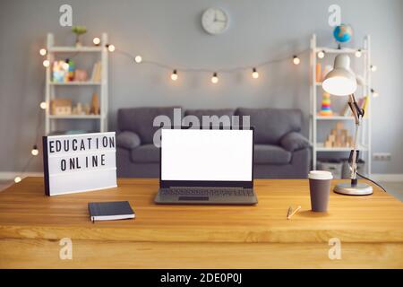 Segno di formazione online e computer portatile con schermo vuoto in piedi su tavolo di legno in soggiorno, mockup per il design Foto Stock