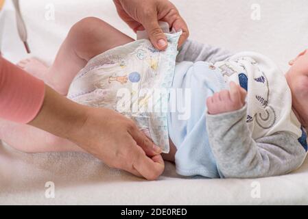 Madre che cambia pannolino di adorabile bambino con un set di igiene per i bambini sullo sfondo Foto Stock