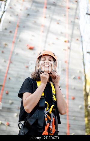 Ritratto di una giovane donna ben attrezzata in piedi davanti della parete di arrampicata al parco divertimenti Foto Stock