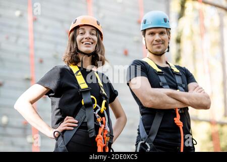 Ritratto di una coppia attiva e ben attrezzata pronta a salire muro al parco divertimenti all'aperto Foto Stock