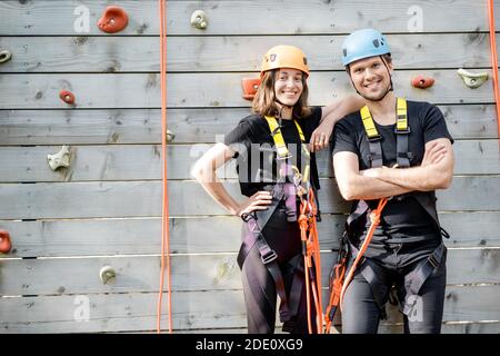 Ritratto di una coppia attiva e ben attrezzata pronta a salire muro al parco divertimenti all'aperto Foto Stock