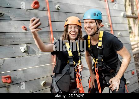 Amici in attrezzature sportive protettive scattando una foto selfie insieme, gli arrampicatori si sentono felici nel parco per l'intrattenimento sportivo Foto Stock