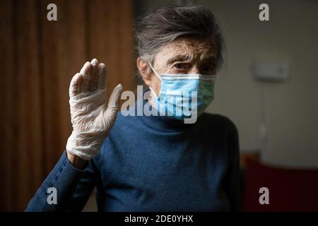 Importanza indossare guanti e maschere per proteggere il coronavirus, in particolare anziani e anziani. Focus su guanti in lattice su sfondo vecchia donna a medica Foto Stock