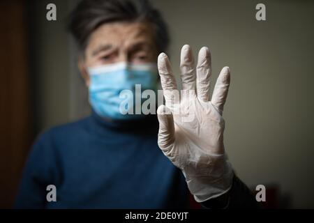 Attrezzatura a tema per la protezione contro infezioni e batteri durante la pandemia del coronavirus. L'importanza di indossare guanti medici per gli anziani, se Foto Stock