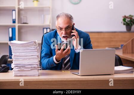 Il vecchio dipendente maschio è insoddisfatto del lavoro eccessivo sul posto di lavoro Foto Stock