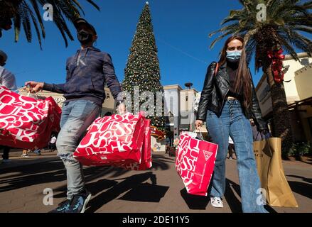 Los Angeles, California, Stati Uniti. 27 Nov 2020. Gli acquirenti che indossano maschere facciali portano borse per lo shopping presso gli outlet Citadel il Black Friday durante la pandemia del coronavirus nel commercio. Credit: Ringo Chiu/ZUMA Wire/Alamy Live News Foto Stock