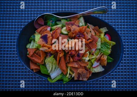 Fatoush (insalata libanese) immagine ravvicinata in un piatto blu . E' fatto con verdure e pane piatto tostato croccante, che insafire il condimento Foto Stock