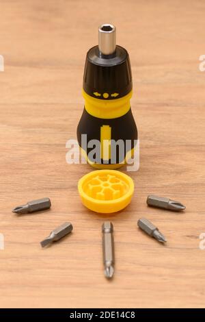 Fotografia a vita di un cacciavite giallo-nero. Fotografia macro dettagliata del set di punte per utensili multiuso compatte e del cacciavite aperti. Foto Stock