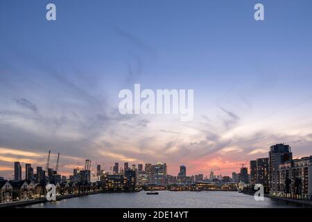Skyline di Londra al tramonto con Canary Wharf e i quartieri finanziari della City of London, la funivia Emirates e Victoria Dock, Londra Foto Stock