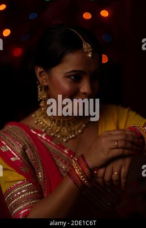 Una giovane e bella donna Bengalese indiana che celebra Diwali in abito tradizionale indiano di fronte a colorate luci bokeh. Stile di vita indiano Foto Stock