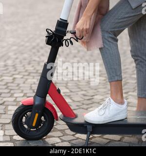 Utente che sblocca scooter elettrico a noleggio. Eco-friendly verde moderno concetto di mobilità urbana di condividere il trasporto con scooter elettrici per il noleggio Foto Stock