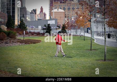 Uomo isolato che pratica le arti marziali con un bastone a Lower Manhattan in un parco nel distretto finanziario. New York City, Stati Uniti Foto Stock