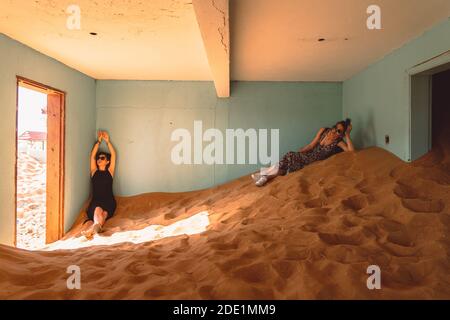 Due Signore nella casa abbandonata piena di sabbia posa sulla sabbia Foto Stock