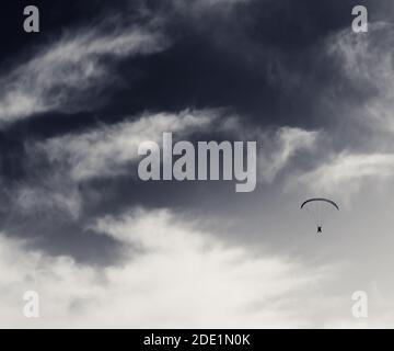 Silhouette di skydiver al cielo ventoso. Immagine retrospettiva in bianco e nero. Foto Stock