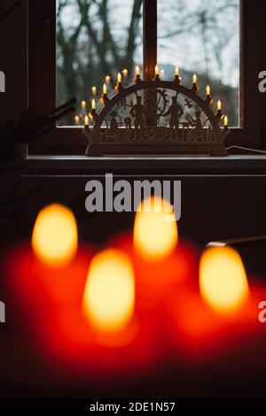 Un fuoco selettivo della corona dell'avvento con il rosso acceso candele e arco a candela nella finestra Foto Stock