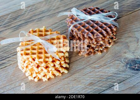 Due pile di deliziosi waffle belgi con miele e cioccolato su tavolo di legno Foto Stock