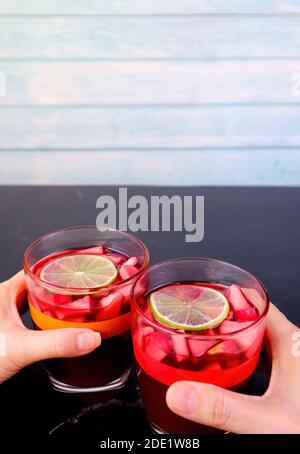 Immagine verticale dell'uomo e della mano della donna che tiene vetro di Vino rosso sangria su Black Table Foto Stock