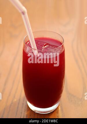Bicchiere di succo di melograno rosso fresco e vivace su tavola di legno Foto Stock