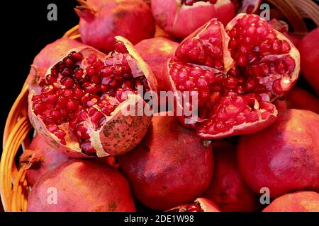 Primo piano VIBRANT Red ha aperto frutta fresca di melograno nel complesso Pile di frutta Foto Stock