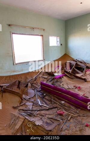 Casa demolita interno sepolto in sabbia, con mobili rotti, nel villaggio fantasma al Madam a Sharjah, Emirati Arabi Uniti. Foto Stock