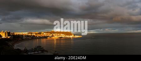 L'ultima luce della giornata a fine novembre, il sole tramontante mette in risalto il promontorio del Castello e il porto e la Città Vecchia di Scarborough, una popolare località turistica Foto Stock