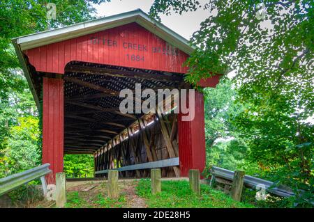 Ripley County, IN--ago 18, 2018; ingresso al ponte di legno rosso coperto di Otter Creek nella rurale Indiana circondato da alberi in estate Foto Stock