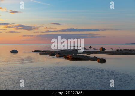 Bellissimo tramonto colorato sulla riva del mare con rocce sotto acque poco profonde Foto Stock