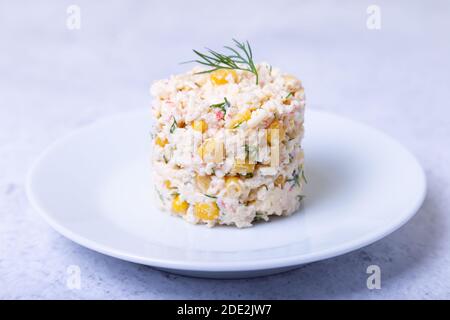 Insalata di granchio con mais e uova su un piatto bianco. Insalata russa tradizionale. Primo piano. Foto Stock