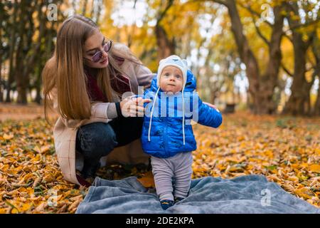 La mamma insegna al bambino a camminare. Giovane madre cammina nel parco con il bambino Foto Stock