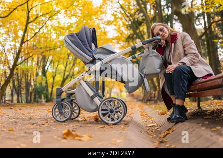 La madre sonnolenta e stanca si siede su una panchina nel parcheggio Foto Stock