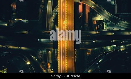In cima alla città illuminano la strada con vista aerea notturna del paesaggio urbano. Bellissimi sentieri di luce all'incrocio al crepuscolo nelle Filippine, la città di Manila. Autostrada Asia con lanterne illuminate. Scatto con drone cinematografico Foto Stock