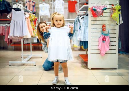 Madre e bambino piccolo provando su vestito in deposito Foto Stock