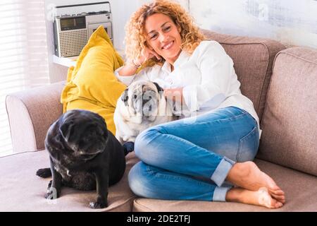 Allegro rilassato donna adulta bella a casa si stese su il divano con i suoi due migliori amici cani pug - concetto di persone e animali infetto terapia totg Foto Stock