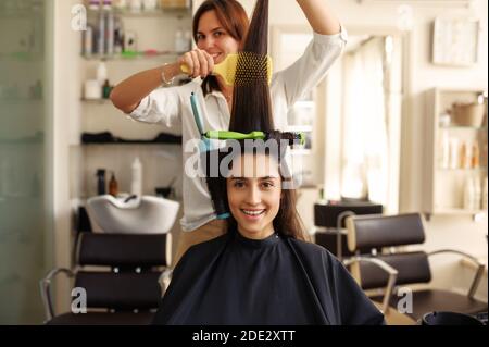 Il parrucchiere ricci e pettini i capelli della donna Foto Stock