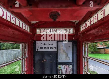 Abbandonato vecchio telefono rosso scatola con rotto smash vetro e. sbucciatura della vernice rossa Foto Stock