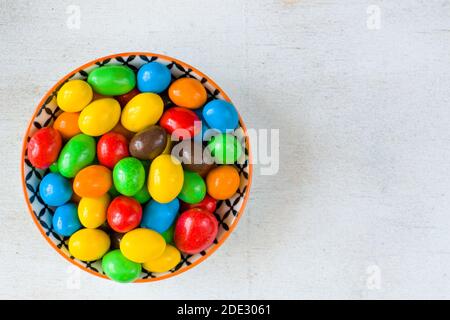 Caramelle di M&M nella ciotola su sfondo bianco, texture caramelle colorate, sfumatura multicolore. Foto Stock