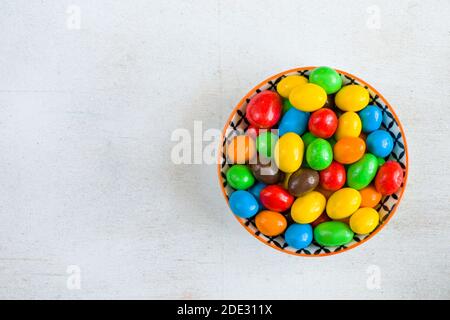 Caramelle di M&M nella ciotola su sfondo bianco, texture caramelle colorate, sfumatura multicolore. Foto Stock