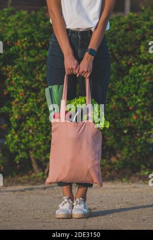 Donna vegana con eco bag riutilizzabile rosa con verdure biologiche fresche. Zero sprechi, concetto privo di plastica Foto Stock