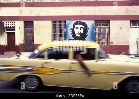 Una foto di che Guevara su un muro e una vecchia auto americana su una strada nella città di l'Avana su Cuba nel mare dei caraibi. Cuba, l'Avana, ottobre 2005 Foto Stock