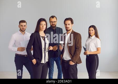 Ritratto di gruppo di giovani uomini d'affari seri in studio guardando la fotocamera Foto Stock