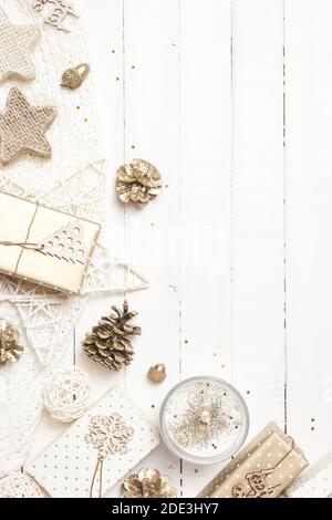 Composizione natalizia o invernale. Regali di Natale, coni di pino, coperta a maglia e ornamenti su sfondo bianco di legno. Disposizione piatta, vista dall'alto, spazio per la copia Foto Stock