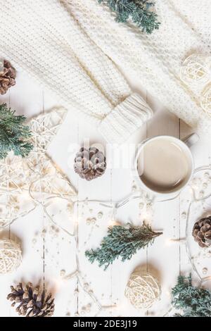 Composizione di Natale. Tazza di caffè, maglia moda donna, rami di abete e ornamenti su sfondo bianco di legno. Inverno, concetto di vacanza. Disposizione piatta Foto Stock