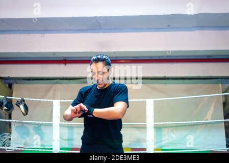 Giovane pugile femmina che si prepara per la lotta di boxe, indossando il cinturino al polso Foto Stock