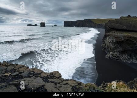 Vista panoramica della spiaggia di Kirkjufjara e della penisola di Dyrholaey contro il cielo nuvoloso, Islanda del Sud, Islanda Foto Stock