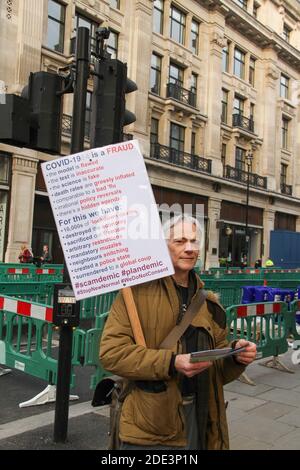 Londra, Regno Unito. 28 Nov 2020. Un manifestante con un cartello che consegna volantini lungo Regent Street durante la dimostrazione.a partire da Marble Arch, i manifestanti anti anti anti-Lockdown si sono spostati verso Piccadilly Circus, dove sono stati posizionati gruppi di ufficiali di polizia completamente attaccati e circa 60 dimostranti sono stati arrestati durante lo scontro. Credit: SOPA Images Limited/Alamy Live News Foto Stock