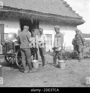 Esercito austro-ungarico durante la prima guerra mondiale. Soldati in piedi intorno a una cucina mobile campo di fronte a una casa di campagna. Un soldato fumatore di sigarette di grado 'korporal' si trova al centro. Data e luogo esatti incerti. Foto Stock